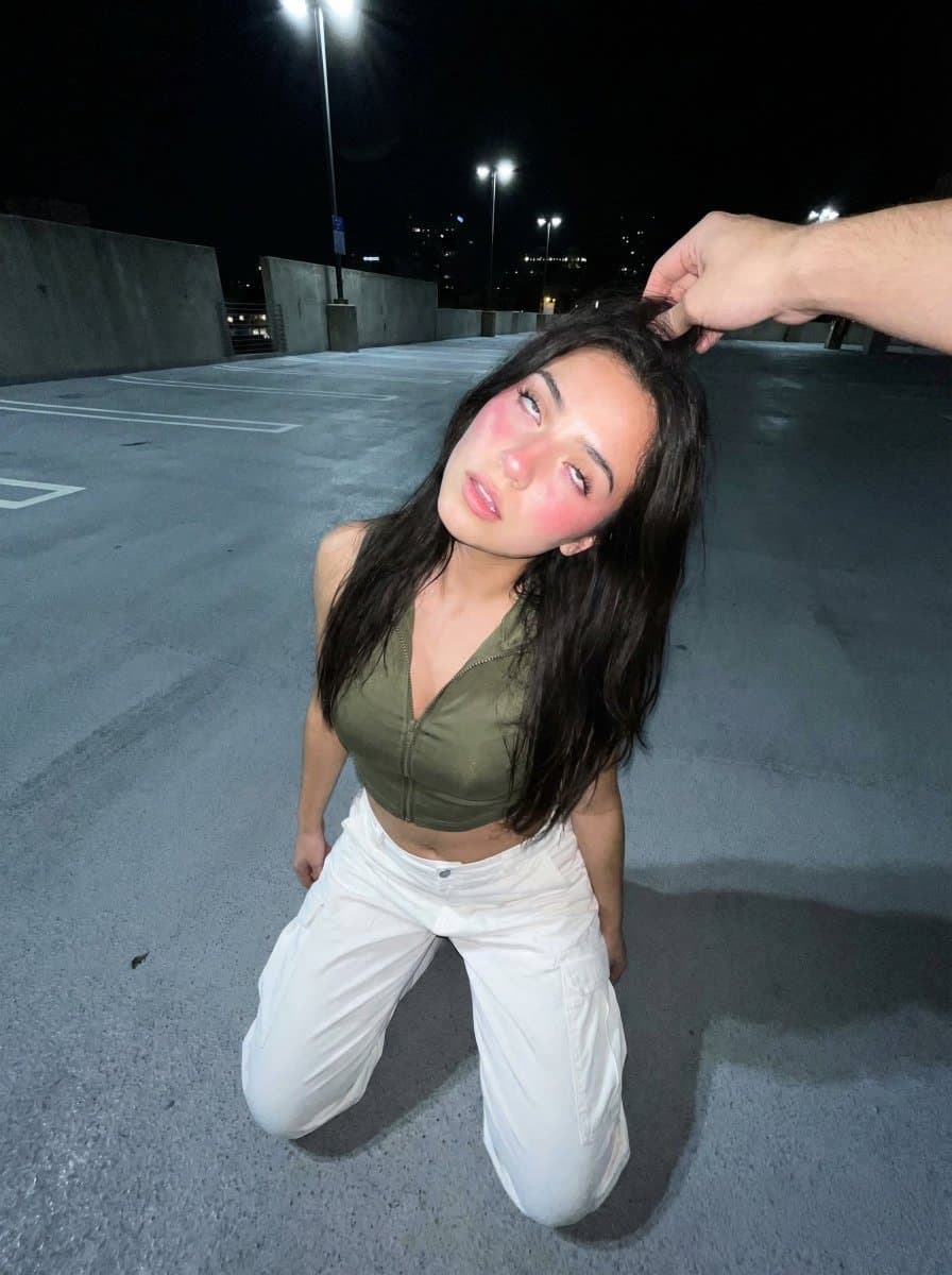 Young Woman Kneeling on Asphalt, Shot from an Outstretched Hand